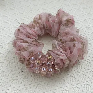 Detailansicht eines eleganten rosa Organza-Haargummis mit funkelnden Kristallperlen