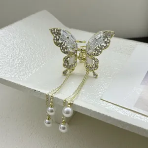 Detail of gold metal butterfly hair claw clip with sparkling rhinestones and pearl tassels