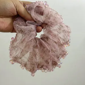 Dettaglio di un elastico in organza a fiori rosa con perline di cristallo iridescenti