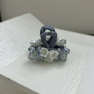 Vue détaillée d'une pince à cheveux avec perles bleues et fleurs de muguet blanches.