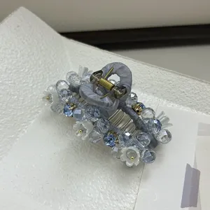 Gros plan sur une pince à cheveux féerique ornée de perles bleues et de fleurs blanches