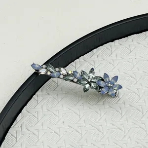 Close-up detail of an elegant floral crystal hair clip resting on a white woven background.