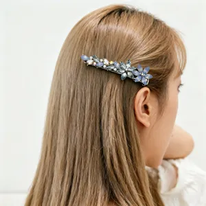 Detailed close-up view of an elegant blue crystal floral hair clip on a model's hair.