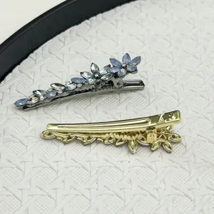 Detail shot of sparkling crystal flower duckbill hair clips in gold and silver finish.