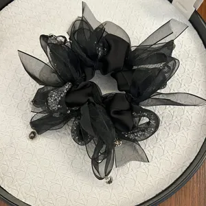 Détail d'un chouchou à nœud en résille noire avec cristaux et perles pendantes
