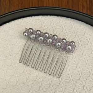 Détail d'un peigne à cheveux avec perles grises et cristaux sur fond tressé