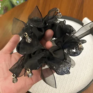 Vue détaillée d'un chouchou noir en ruban avec des strass brillants et des breloques perlées