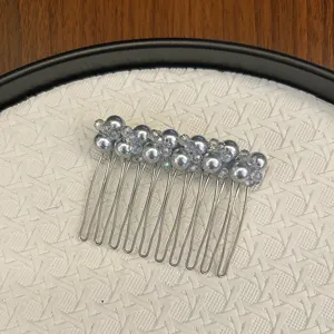 Vue détaillée de perles grises et de cristaux sur un peigne à cheveux en métal argenté.