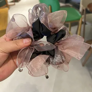 Vue détaillée d'un chouchou en organza élégant avec des paillettes et des pendentifs en cristal.