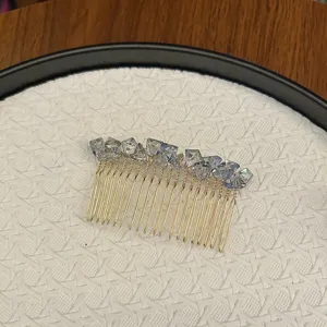Elegant gold-tone hair comb with faceted light blue crystals on a white textured tray.