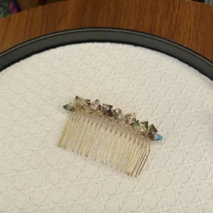 Close-up view of a gold-toned crystal hair comb with faceted smoky stones.