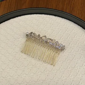 Detailed view of elegant crystal hair comb with gold metal tines on textured background