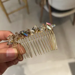 Close-up of an iridescent crystal hair comb with elegant gold-plated metal teeth.