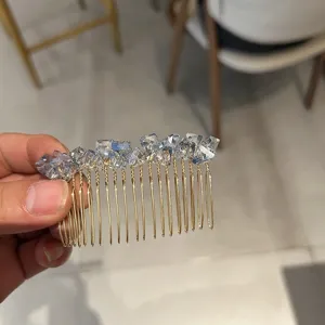 Close-up detail of a faceted light blue crystal hair comb with gold finish base