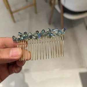 Close-up detail of an elegant gold hair comb decorated with iridescent blue crystals