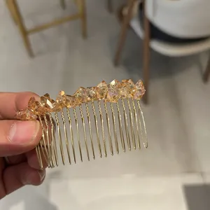 Detail of a golden hair comb featuring sparkling champagne crystals held by hand