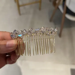 Detail showing hand-held crystal hair comb with elegant gold-tone metal teeth