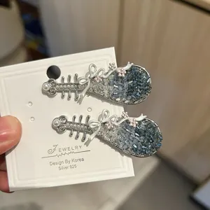 Detailopname van Pipa-haarspeldjes met blauwe kristallen en kleine strikjes.