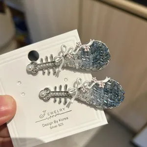 Detailopname van elegante pipa-haarspelden met blauwe kristallen en strikjes.