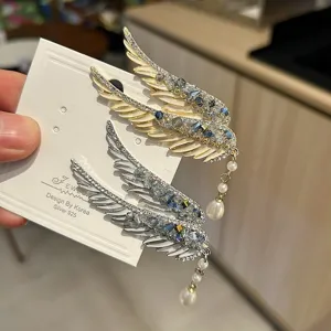 Close-up detail of angel wing hair clips featuring sparkling crystals and pearl tassels