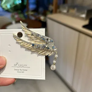 Macro view of luxurious angel wing hair clip with blue crystals and a pearl tassel