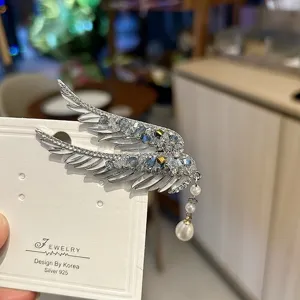 Elegant angel wing hair clip with blue crystals and a dangling white pearl tassel