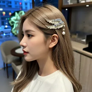 Detail of angel wing hair clip with crystals and pearl tassel on blonde hair
