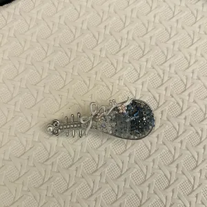 Detailopname van een Pipa-haarspeld met blauwe kristallen en een elegante zilveren strik.
