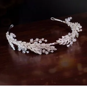 Elegant bridal crystal hair tiara with intricate leaf details shown on dark wood background