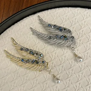 Detailed view of angel wing hair clips featuring luxury crystals and elegant pearl tassels