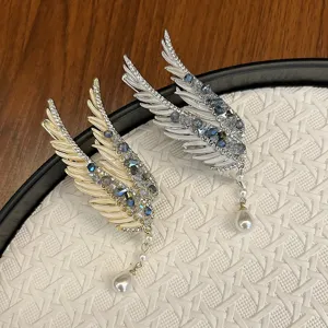 Close-up detail of angel wing hair clips decorated with blue crystals and pearl drops