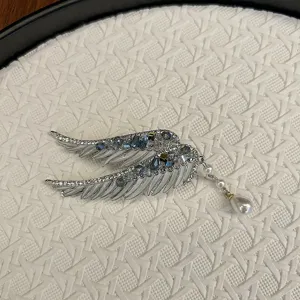 Close-up detail of silver angel wing hair clip with blue crystals and pearl tassel