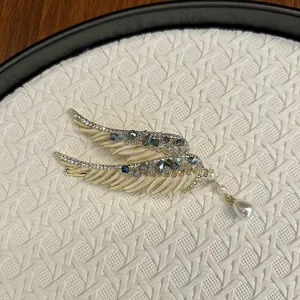 Intricate angel wing hair clip with blue rhinestones and a dangling pearl tassel