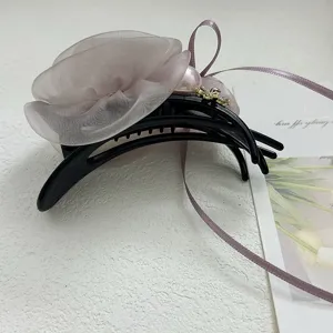 Vue détaillée macro de l'élégante pince à cheveux rose en organza mauve avec perle.