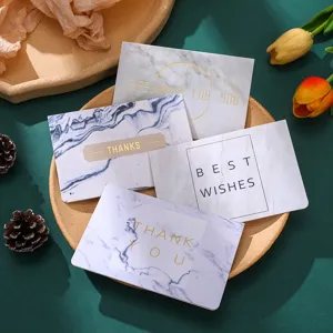 Primer plano de tarjetas de felicitación con motivo de mármol y texto en pan de oro.