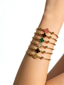 Close-up detail shot of stacked stainless steel four leaf clover bracelets on a clean wrist.