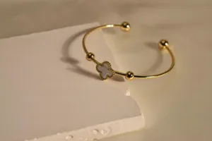 Gold-plated stainless steel cuff bracelet featuring a delicate mother-of-pearl clover.