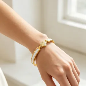 Bracelet coeur en acier dore avec strass scintillants et incrustation blanche en detail.