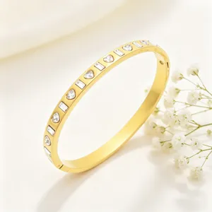 Gros plan sur un bracelet en acier titane doré orné de zircons en forme de cœur et de baguette.