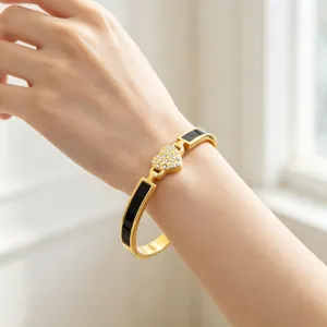 Vue détaillée du bracelet jonc doré en acier avec émail noir et cœur en cristal étincelant.