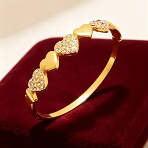 Gros plan détaillé du bracelet en or avec cœur et strass, montrant des breloques brillantes.
