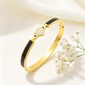 Elégant bracelet jonc en acier inoxydable doré avec cœur en strass et accents noirs.