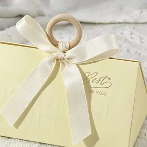 Close-up of triangular gift box with a wooden ring handle and cream ribbon knot detail.