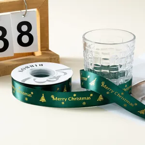 Vista detallada de cinta de raso verde oscuro con diseño de Feliz Navidad en oro.