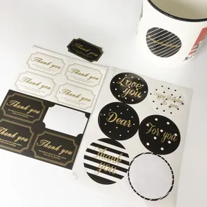 Detail of gold foil Thank You stickers on black and white circular and square sheets.