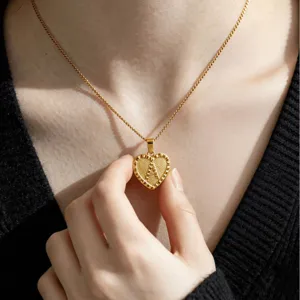 Close-up of gold-plated stainless steel heart letter pendant necklace with curb chain.