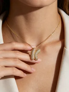 Close-up detail of a gold-plated bubble letter pendant necklace with sparkling pave diamonds.