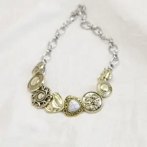 Macrodetail van vintage messing knoopbedels en marmeren hart aan een titanium ketting