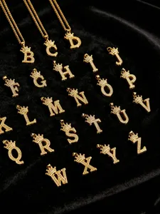 Detailaufnahme eines goldenen Kronen-Buchstaben-Anhängers mit Zirkonia auf Samt.