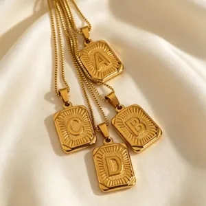 Nahaufnahme von goldenen Edelstahl-Boxkettchen mit rechteckigen Buchstaben-Anhängern.